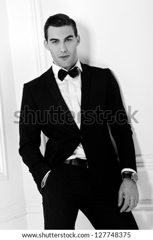 Man in black dinner jacket with bow tie. Bridegroom. Black-and-white photo.