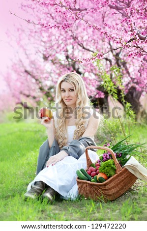 woman with picnic crib eating apple on the green grass