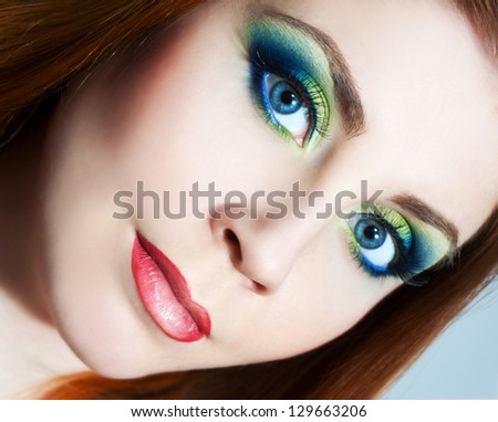 Closeup beauty portrait of attractive model face with bright visage. Multicolored eye makeup and pink lips make-up