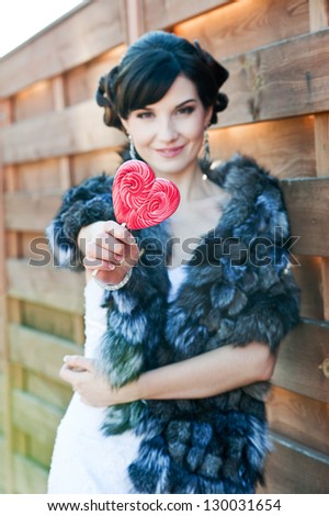 Beautiful smiling bride with red lollipop. Wedding