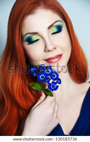 Closeup beauty portrait of attractive red-haired model face with bright visage. Multicolored eye makeup and pink lips make-up