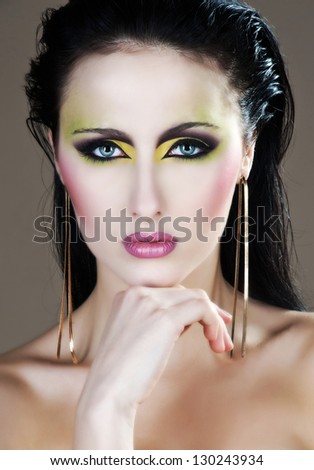 Closeup beauty portrait of attractive model face with bright visage. Multicolored eye makeup and pink lips make-up