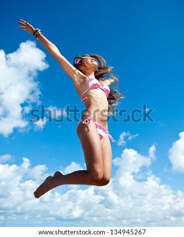 Jumping & dancing happy girl on the beach, fit sporty healthy sexy body in bikini, woman enjoys wind, freedom, vacation, summertime fun concept