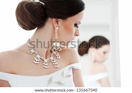 Beautiful Bride Brunette Girl In White Wedding Dress With Hairstyle And Bright Makeup Looks In The Mirror