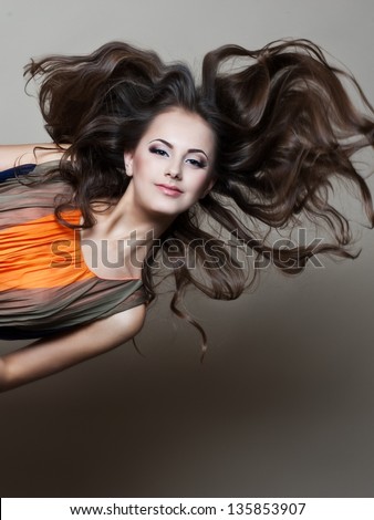 Beautiful woman with evening make-up and evening hairstyle. Jewelry and Beauty. Fashion photo. Flying hair.