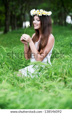 Beautiful  smiling young girl outdoors in spring. Wreath of daisies