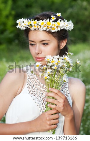 Beautiful woman enjoying daisy field, pretty girl relaxing outdoor, having fun, holding plant, happy young lady and spring green nature, harmony concept