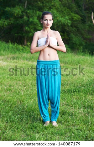 young woman practices yoga in the park