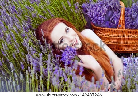 Beautiful girl on the lavender field. Young red-haired girl collects lavender