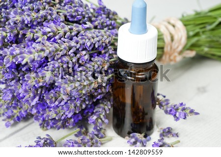 bottle of lavender oil and bunch of lavender flowers
