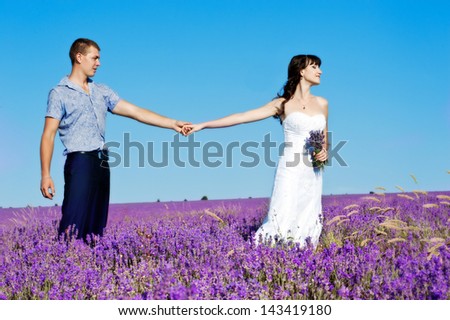 A young couple in love bride and groom, wedding day in summer. Enjoy a moment of happiness and love in a lavender field. Bride in a luxurious wedding dress on a background bright blue sky