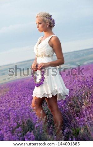 Beautiful bride on the lavender field. Young woman with blond hair collects lavender