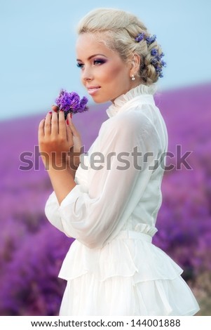 Beautiful bride on the lavender field. Young woman with blond hair collects lavender