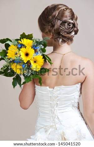 The bride with a wedding bouquet is turned by back. Hairstyle.