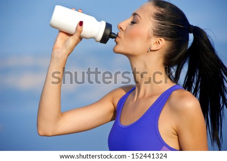 Portrait of cheerful young attractive woman drinking water, outdoors