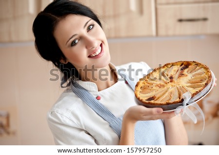 Smiling woman cook holds apple pie.