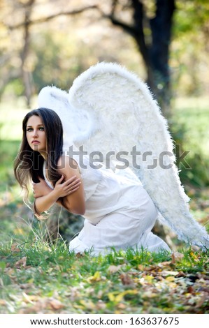 Beautiful angel with white light wings posing outdoor. Beautiful angel woman