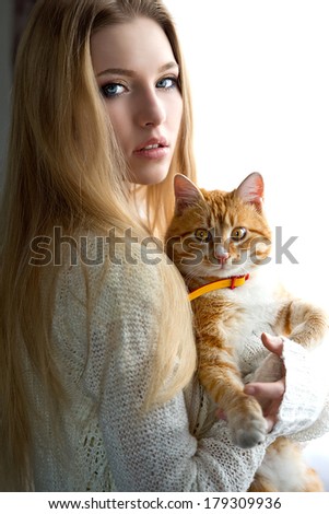 Portrait of the blonde woman with cat near window
