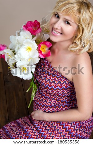 Pregnant woman holding in hands bouquet of flowers, new life concept