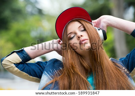 young attractive girl in urban background listening to music with headphones