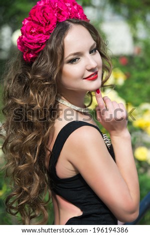 Beautiful woman in wreath in the garden of  roses