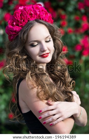 Beautiful woman in wreath in the garden of  roses