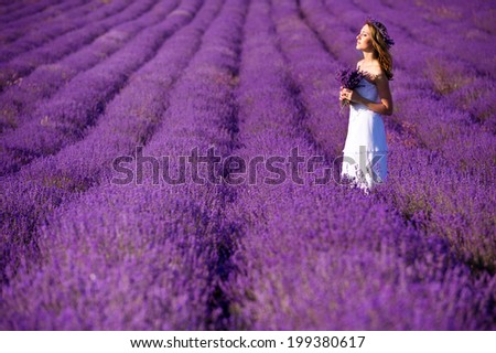 Beautiful Bride in wedding day in lavender field. Newlywed woman in lavender flowers. Young woman in wedding dress outdoors.