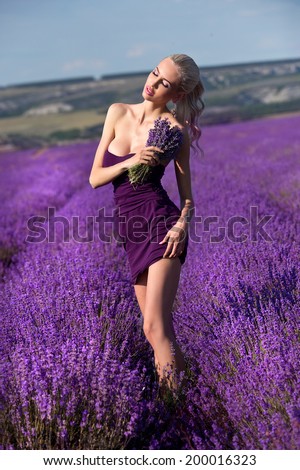 Beautiful girl in on the lavender field. Young woman with long hair collects lavender