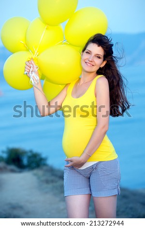 pregnant woman with yellow balloons