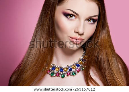 Close-up of beautiful woman face with colorful make-up and lips. Woman with colorful necklace