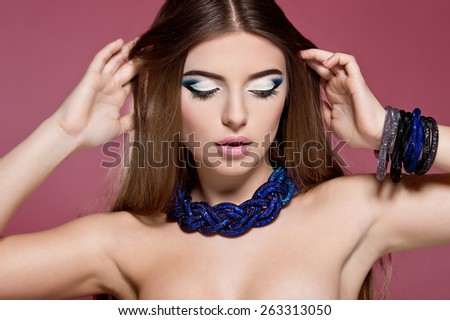 Close-up of beautiful woman face with colorful make-up and pink lips. Woman with jewelry .