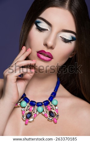 Close-up of beautiful woman face with colorful make-up and pink lips. Woman with jewelry.