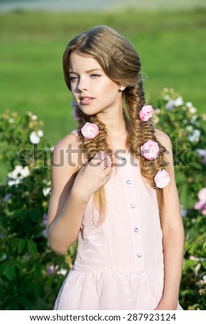 Beautiful girl with braids in garden of roses