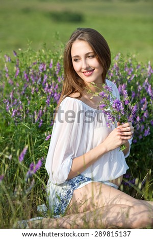 Happy pregnant woman with flower in meadow flowers, sunset time, new life concept