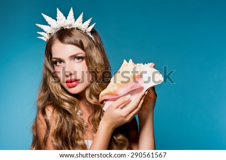 Beautiful girl holding a shell. Mermaid. Sound of the sea in a shell.