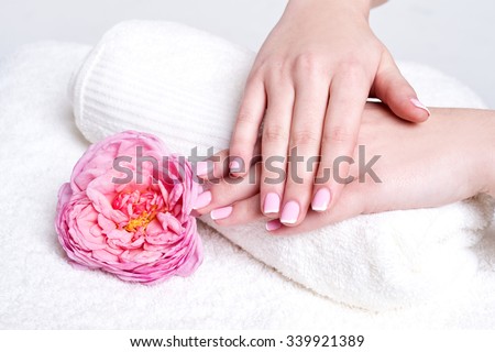 Woman hands with french manicure and rose flowers on towel