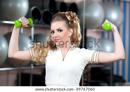 Portrait of fitness woman working out with free weights in gym