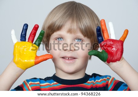 Five year old boy with hands painted in colorful paints ready for hand prints