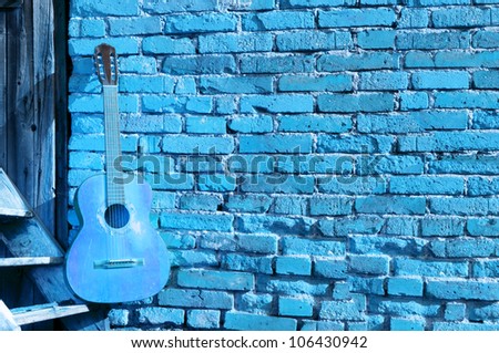 blue guitar on the steps with blue brick background horizontal