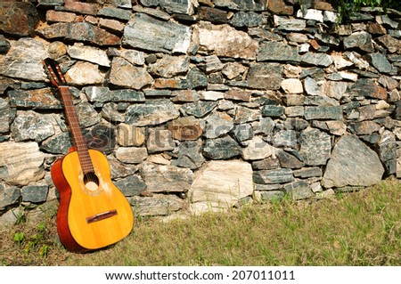 Spanish guitar propped up by the stone wall as background