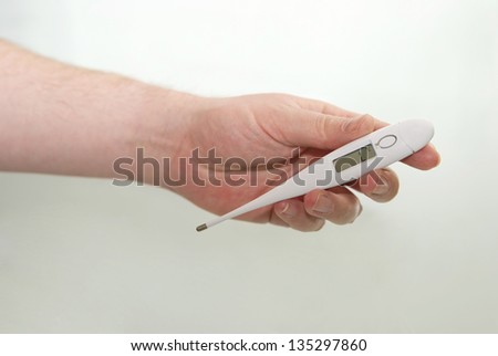 Man\'s hand holding a white digital thermometer