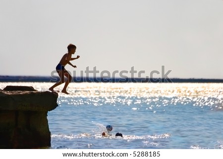 The boy jumping in water from a pier