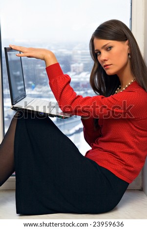 Young woman with laptop computer on window-sill