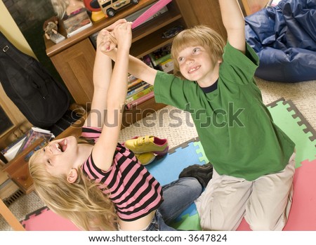 Adorable twins wrestling/playing keep-away on the playroom floor.