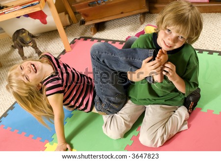 Adorable twins tickling on the playroom floor.