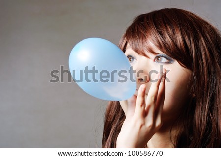 portrait of middle aged woman blowing a balloon against a grunge wall