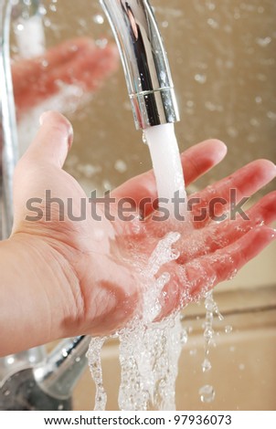 A person washing their hands in the bathroom sink
