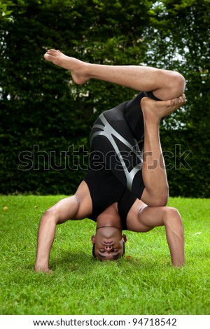 Handsome Indian man practicing yoga outside.