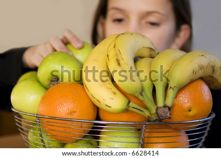 girl takes apple from fruit bowl