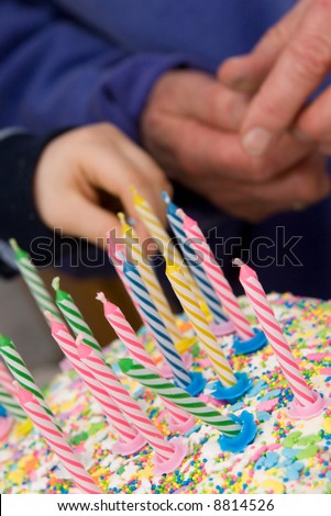 birthday cake with candles - old and young hands in background